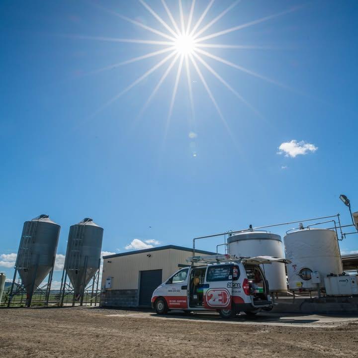 Photo of a farm with silos and a 2E electrical van parked in front of electrical farming equipment